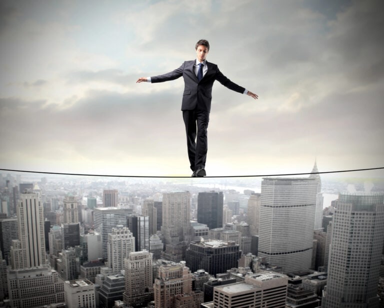 Businessperson walking on a tightrope above a city skyline