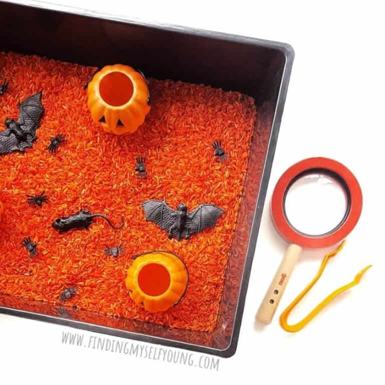 Spooky sensory tray featuring orange rice and creepy crawlies