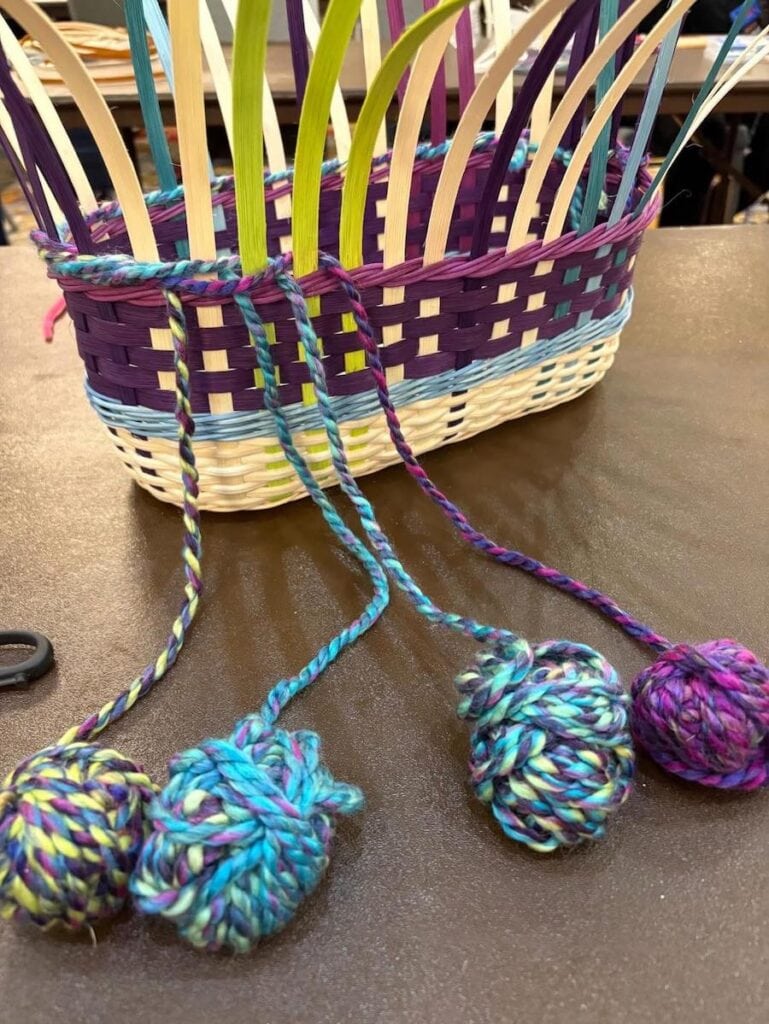 Four balls of yarn connected to half-finished reed basket
