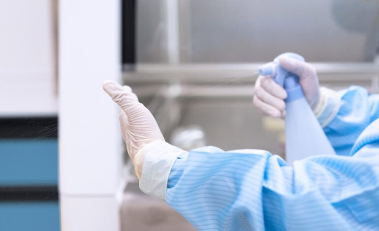 gros plan de la main d'un microbiologiste en train de pulvériser un désinfectant pour nettoyer la main