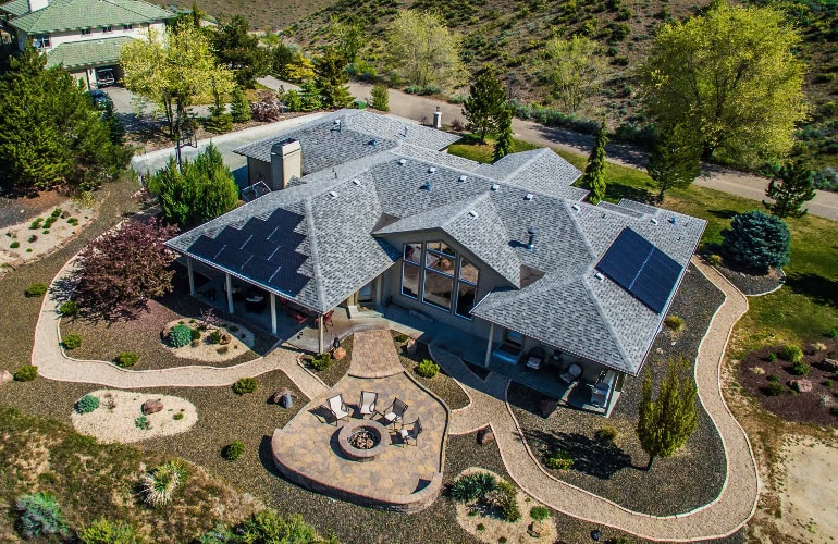 Aerial view of home in Idaho with solar panels on the roof, and surrounded by trees and landscaping