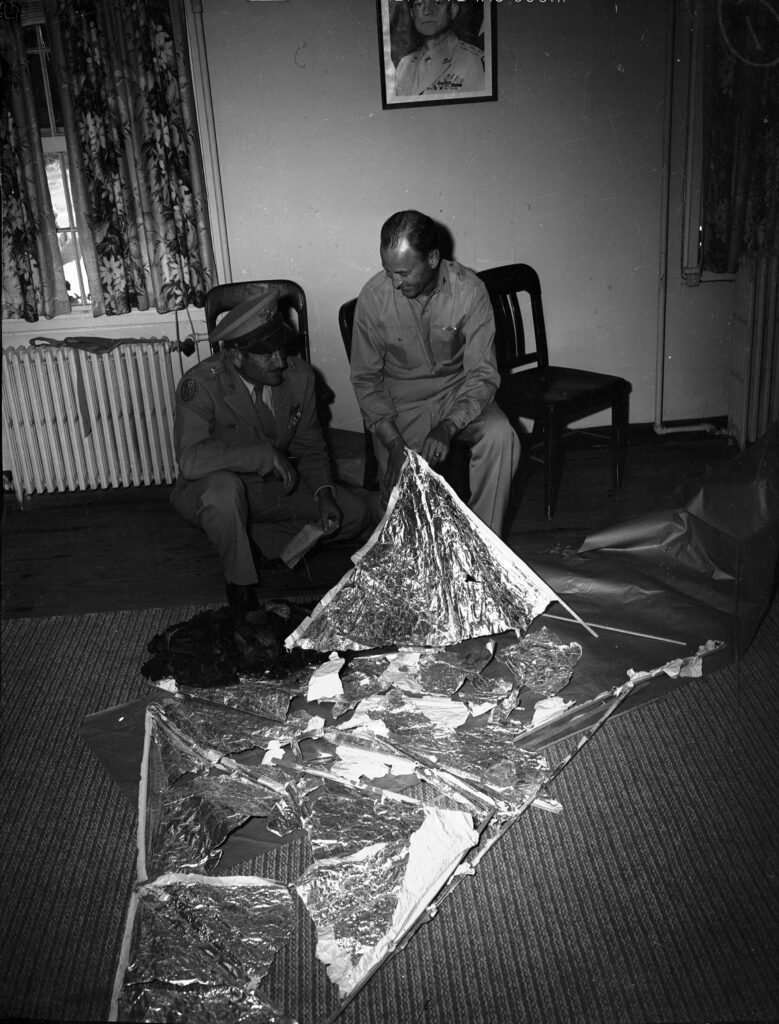 a man sitting on the floor holding a foil object. Roswell Incident