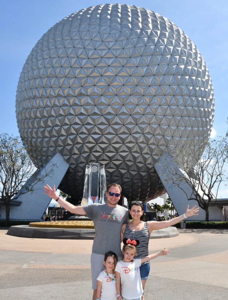 Famous EPCOT geodesic sphere at Disney World with happy family in front, celebrating Orlando vacations.