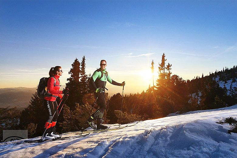 Férfi és nő síel a Magas-Tátrában napfelkeltekor Tátralomnic közelében