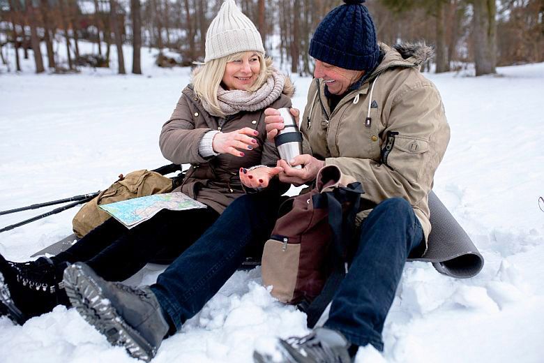 Téli túrázás közben pihen egy nő és egy férfi és közben termoszból isznak.