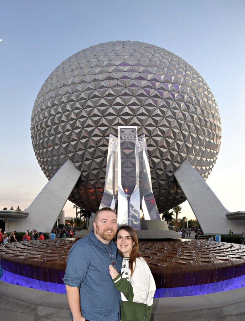 Iconic Epcot geodesic sphere at night with visitors in front.
