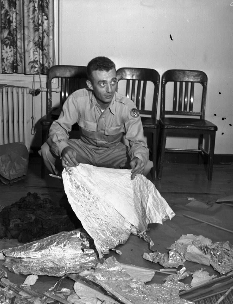a man sitting on the floor holding a foil object. Roswell Incident