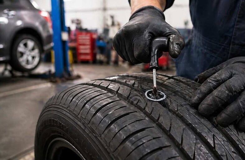 Mechanic patching a punctured car tire in garage