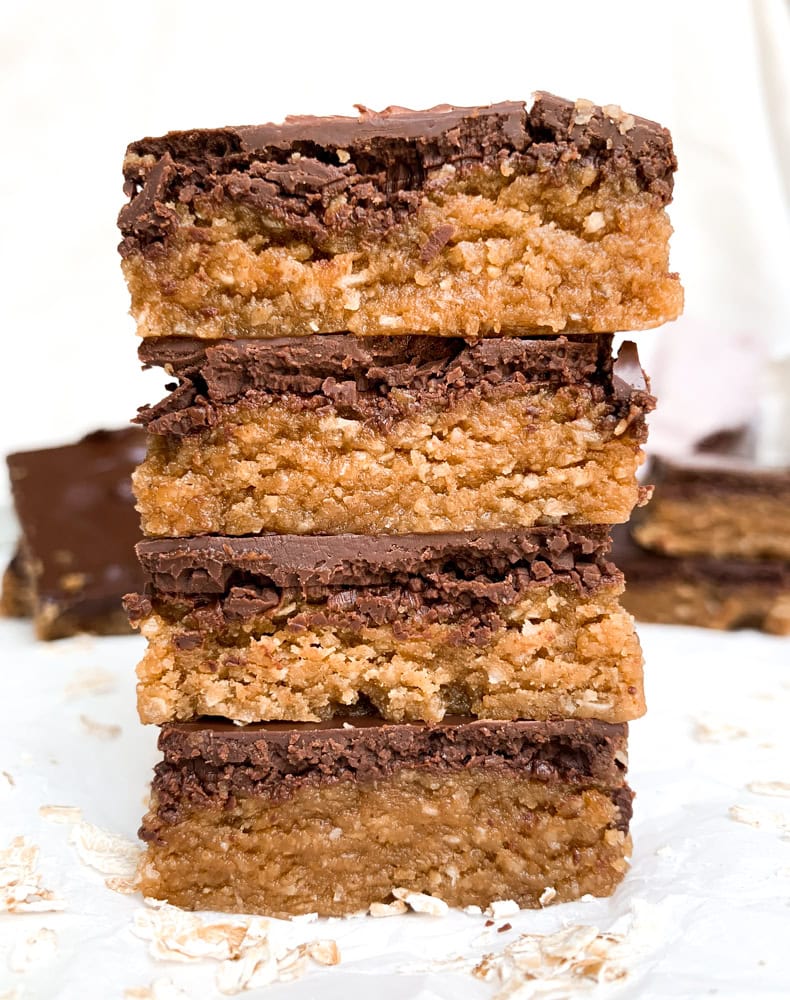 close up, front angle of a stack of peanut butter oatmeal cookie dough bars with a white background