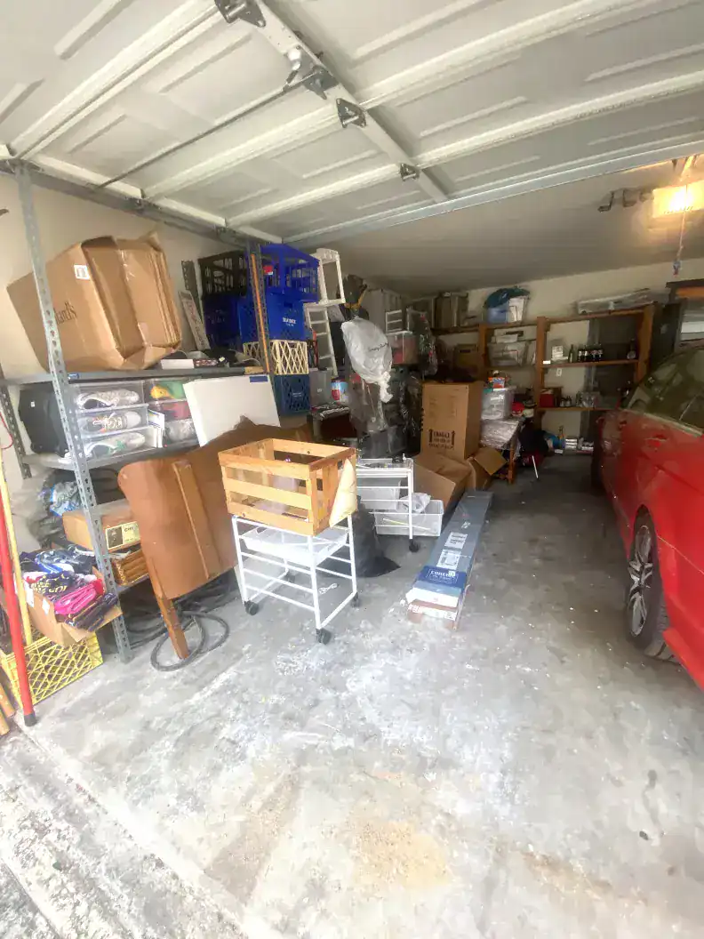 Cluttered garage storage with shelves, boxes, and a red car, showcasing organization and space management for home decluttering and storage solutions.