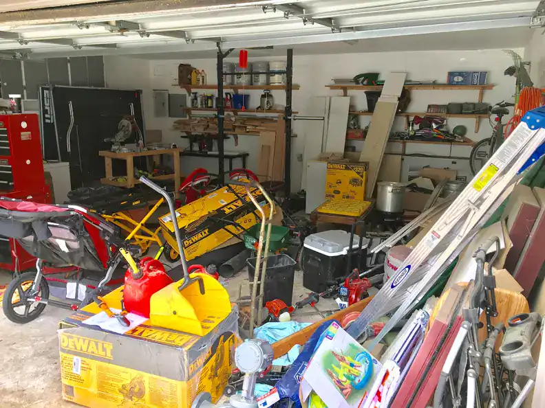 Debris-filled garage storage organization with tools and equipment, cluttered workspace for DIY projects, showcasing a variety of power tools, ladders, and household items for home improvement and repairs.