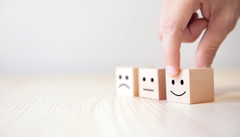 Close up customer hand choose smiley face and blurred sad face icon on wood cube, Service rating, satisfaction concept.Close up customer hand choose smiley face and blurred sad face icon on wood cube, Service rating, satisfaction concept.