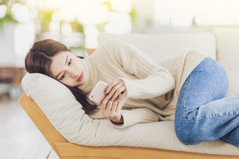 young woman resting at home on the sofa and watching the  mobile phone