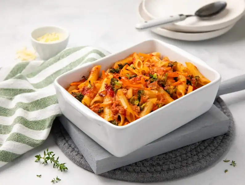 Massa no forno com atum e legumes servida numa travessa, com vegetais visíveis e crosta dourada.