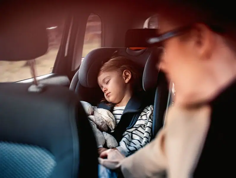 Pai a observar bebé a dormir no assento do carro.