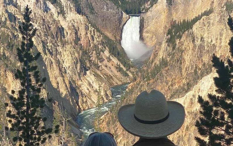 A couple observes Yellowstone Falls at Artist Point Overlook. Taken on a private tour with Teton Excursions in Yellowstone National Park.