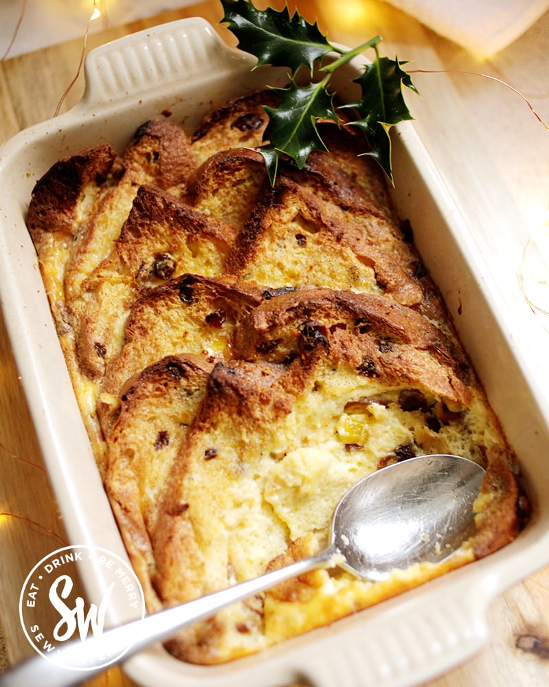 Panettone Bread and Butter Pudding in the Le Creuset dish ready to be served decorated with a sprig of holly. 