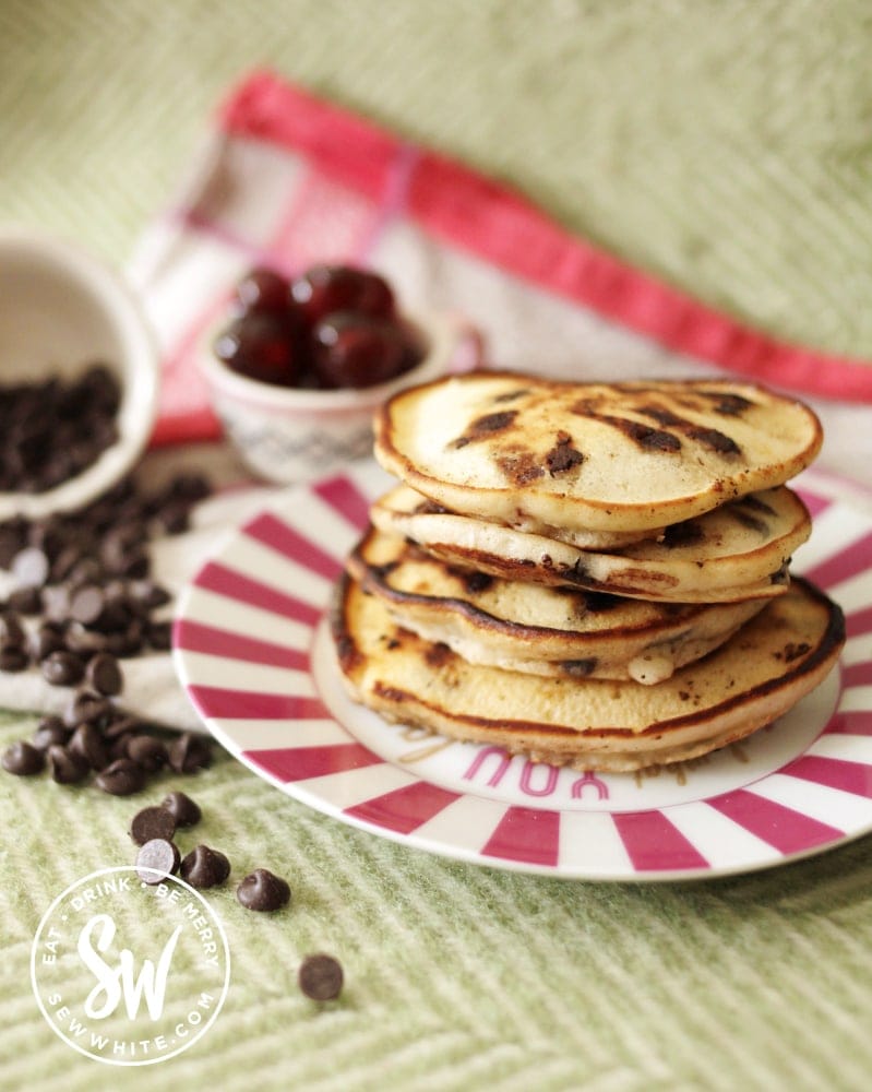 Easy cherry chocolate pancakes stack on a pink plate. 