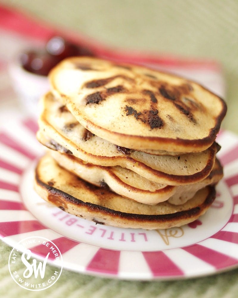 A golden brown stack of chocolate cherry pancakes on a pink stripe plate.