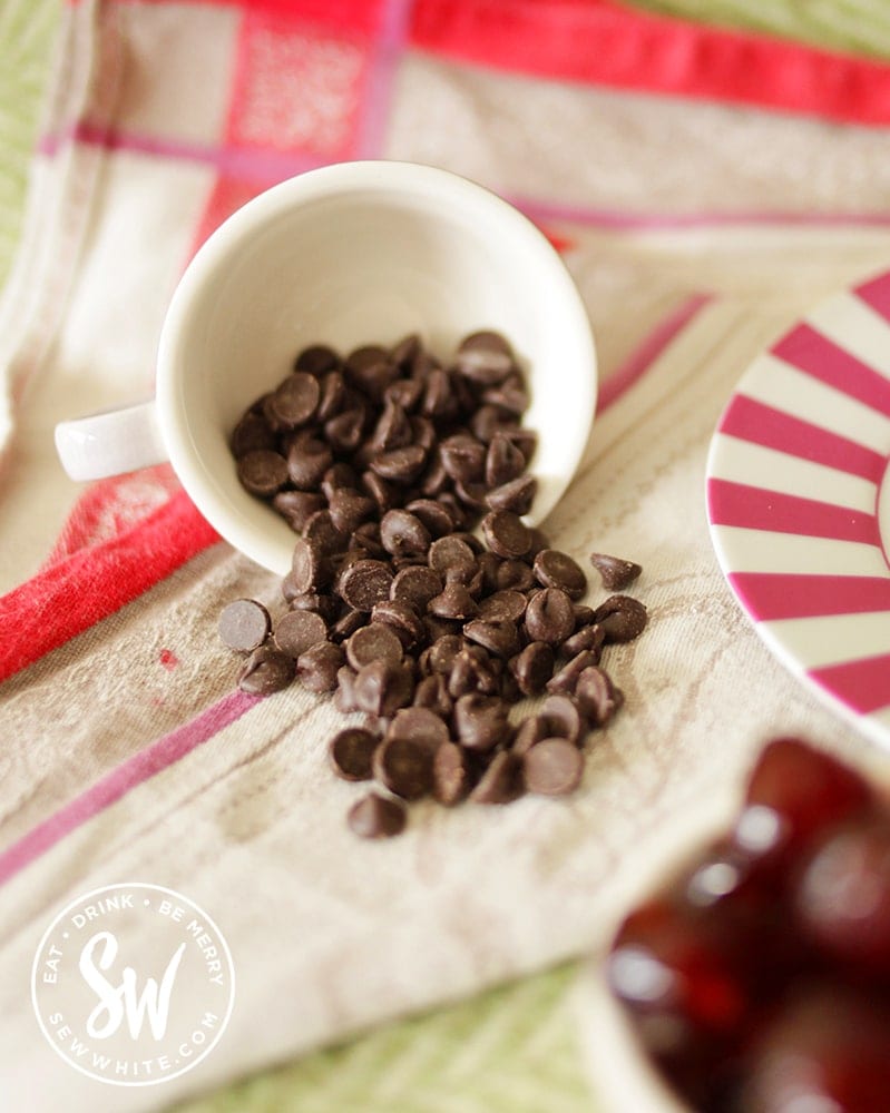 A cup full of chocolate chips falling out on to a table