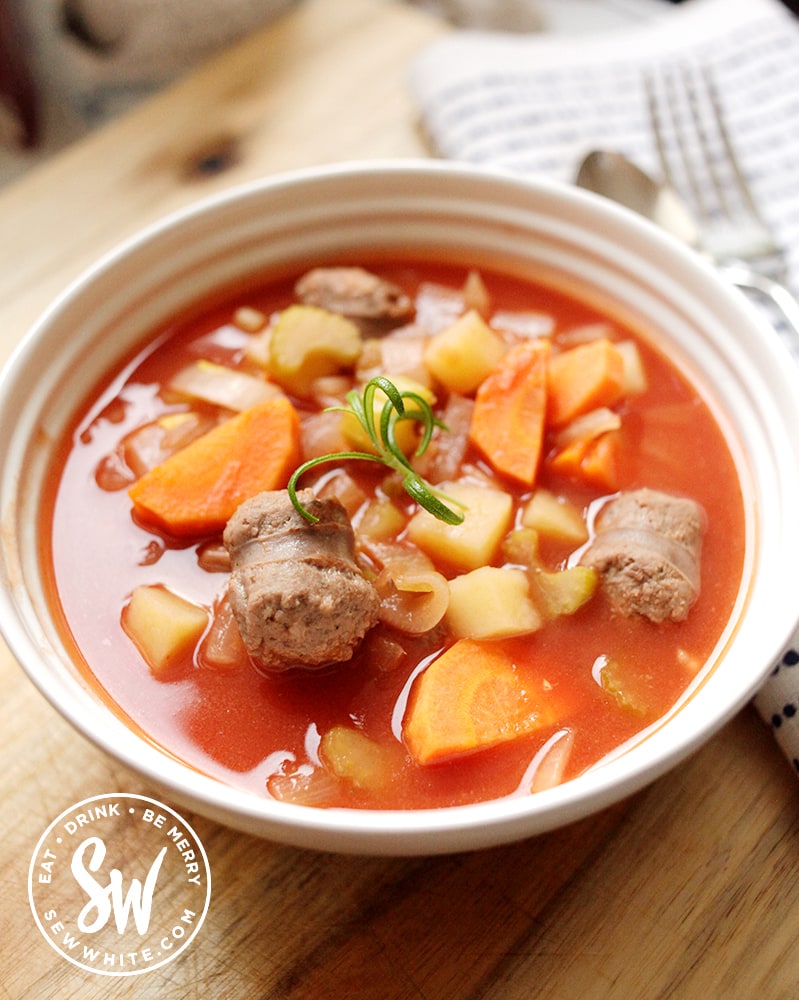 Pieces of venison in a red stew with carrots and potatoes for the Slow Cooker Sausage Stew. Decorated with fresh rosemary.