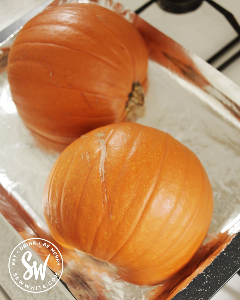 pumpkin halves face down on a baking tray ready to roast.