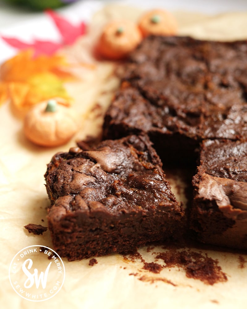 A corner slice of the golden pumpkin brownies on a piece of greaseprrof paper