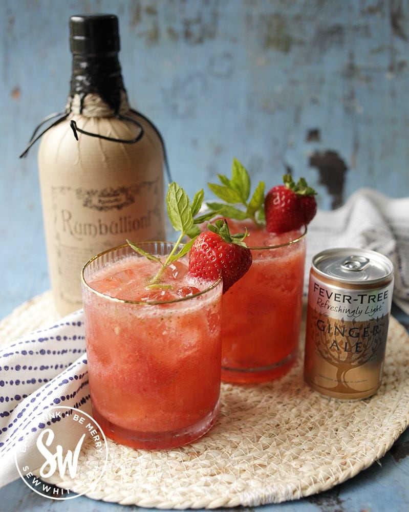 bright red and vibrant strawberry rum cocktail decorated with fresh mint and strawberry