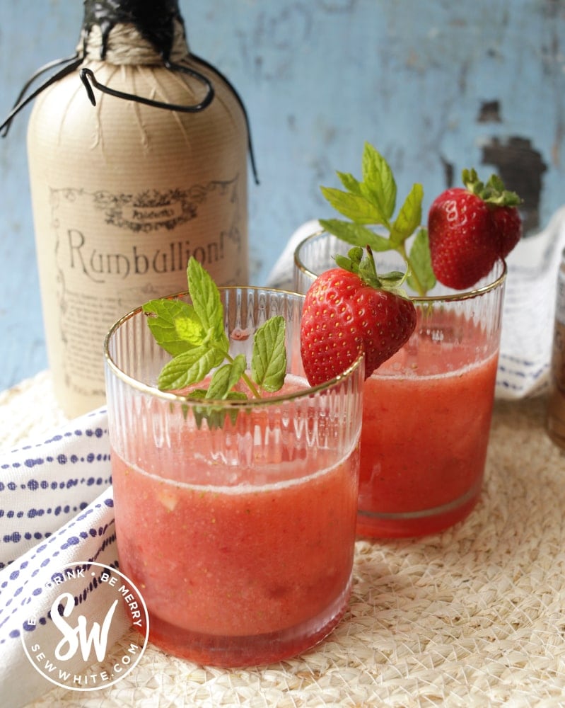 strawberry rum cocktail  in gold rimmed glasses with fresh strawberries and mint