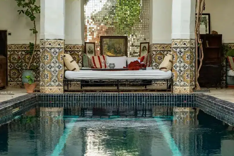 Indoor pool surrounded by a bed and a couch, showcasing a cozy living space in a Moroccan home.