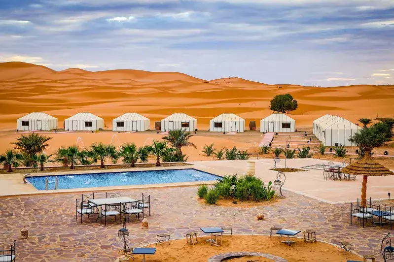 A serene pool surrounded by desert scenery at a Moroccan camp, showcasing the beauty of Custom Morocco Tours.