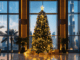 Weihnachten in Dubai - ein Tannenbaum steht in der Lobby in Dubai, im Hintergrund sind Palmen und der Burj Khalifa