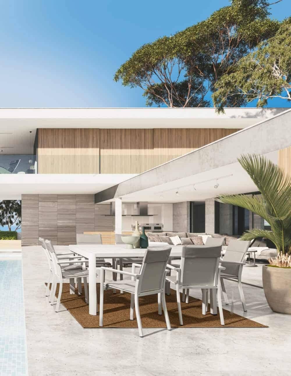 Villa moderna con piscina e zona pranzo all'aperto, arredi esterni eleganti e vista su alberi.