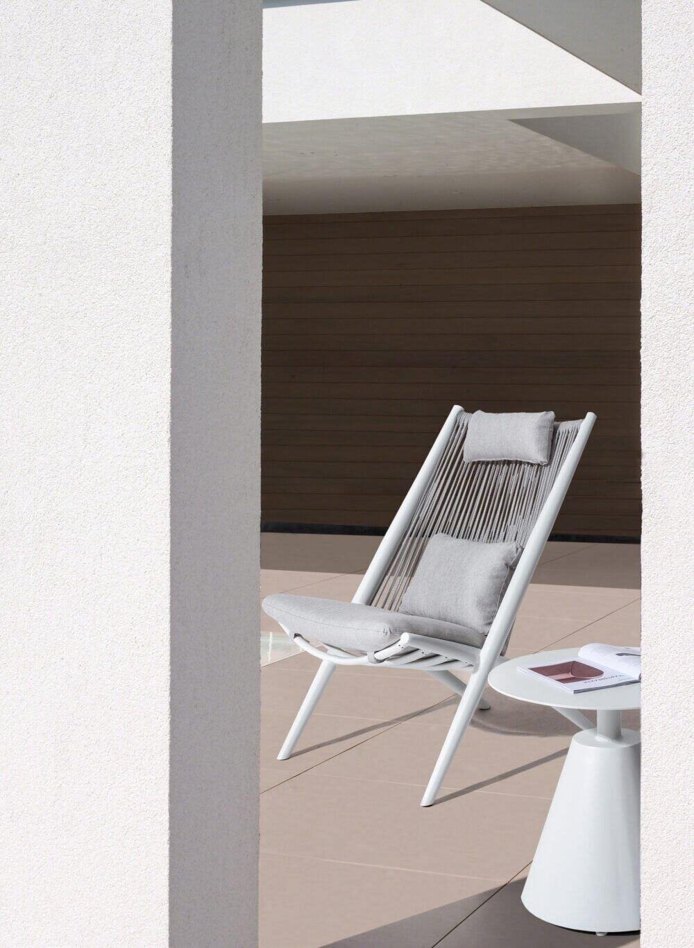 Sedia da esterno moderna con cuscini in tessuto grigio.