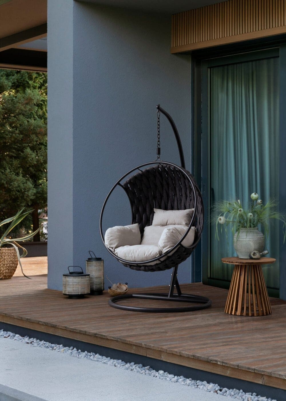 Sedia sospesa in metallo nero con cuscini per relax in giardino o terrazza.