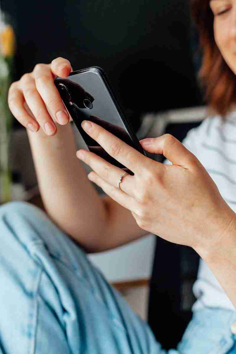 Woman looking at phone representing how being on social media can increase symptoms of anxiety. Start online anxiety treatment in Michigan today.