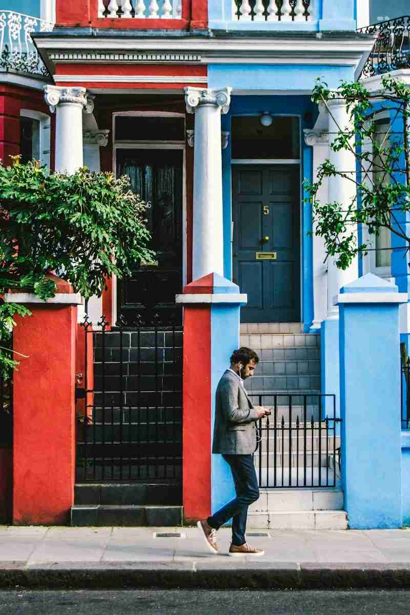 A man in a jacket walking down a city sidewalk looking at his phone, moving through the day the way complex PTSD can feel.
