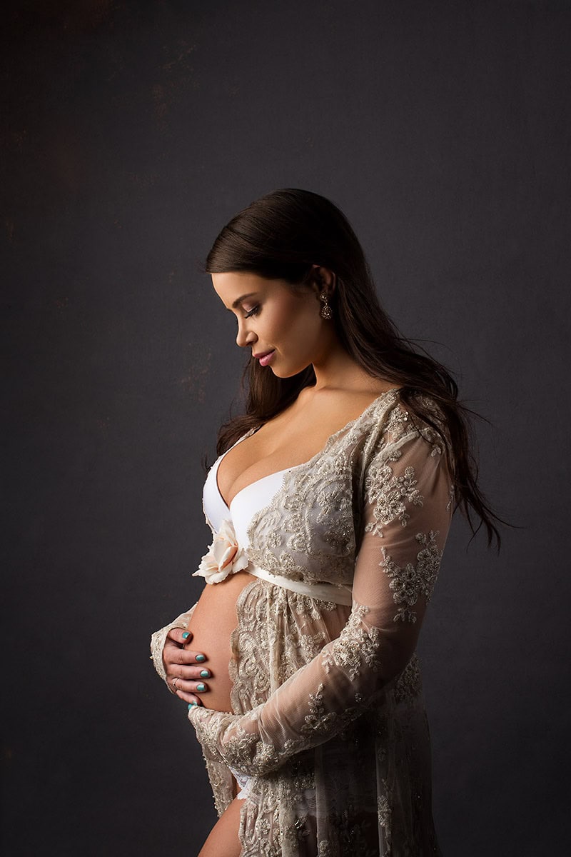 Smilende gravide kvinne i elegant brudekjole med hånd på mage, studerer sitt svangerskap, gravidfotografering, vakker minne.