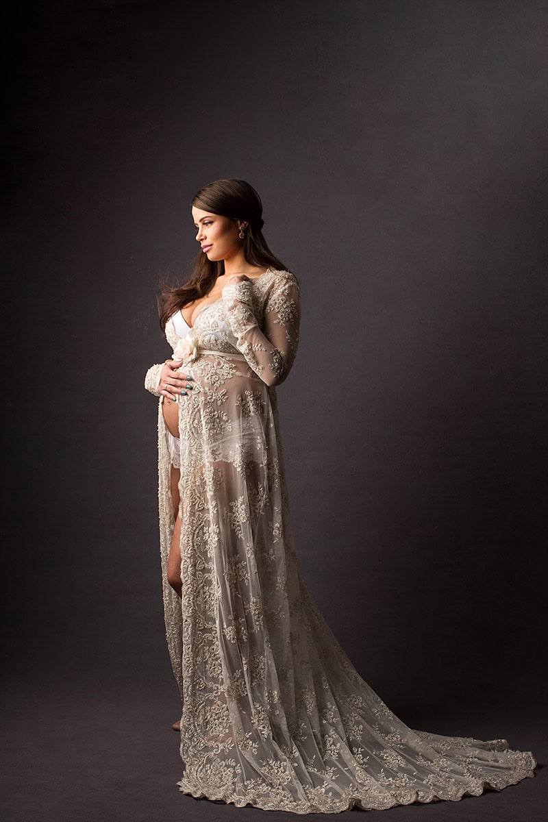 Vakker gravidfoto av en kvinne i elegent blonde kjole, som fremhever gravidmagens skjønnhet mot en mørk bakgrunn. Perfekt for gravidfoto, mamatfotografering og mamedokumentasjon.