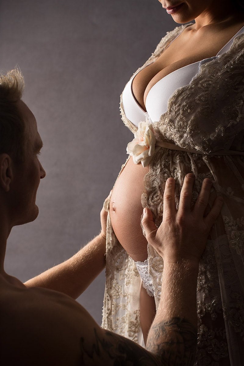 Kjærlighetsfull gravidfotografering av ventende mor med partner, fokus på gravidmage og intime øyeblikk, profesjonell gravidfotograf, fine mesterverk for gravide og forberedelse til fødsel.