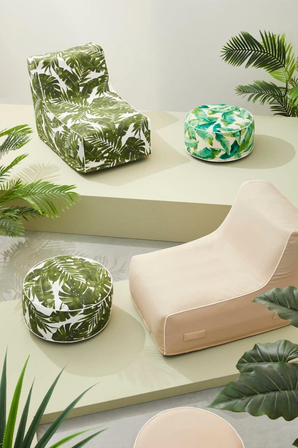 Poltrona e pouf con stampa foglie tropicali, arredamento contemporaneo e atmosfera naturale.