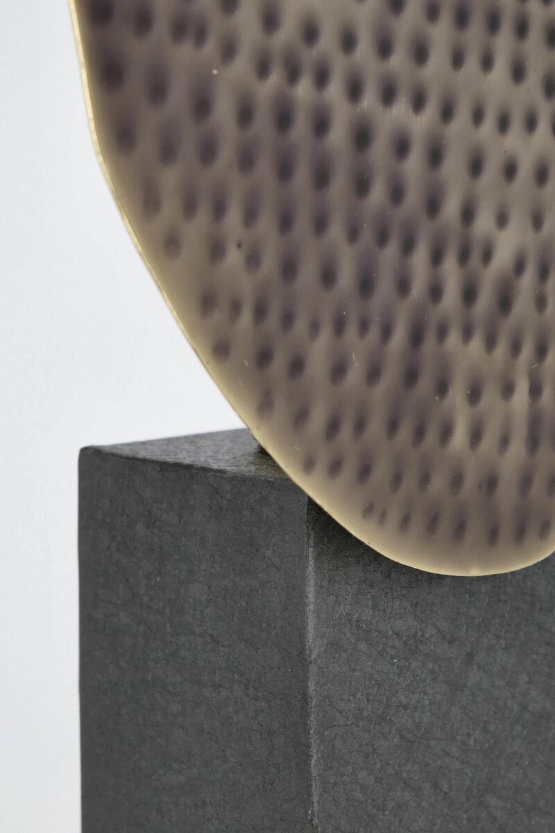 Statuetta in ceramica con superficie traforata, posizionata su base in pietra, ideale per arredi di lusso.