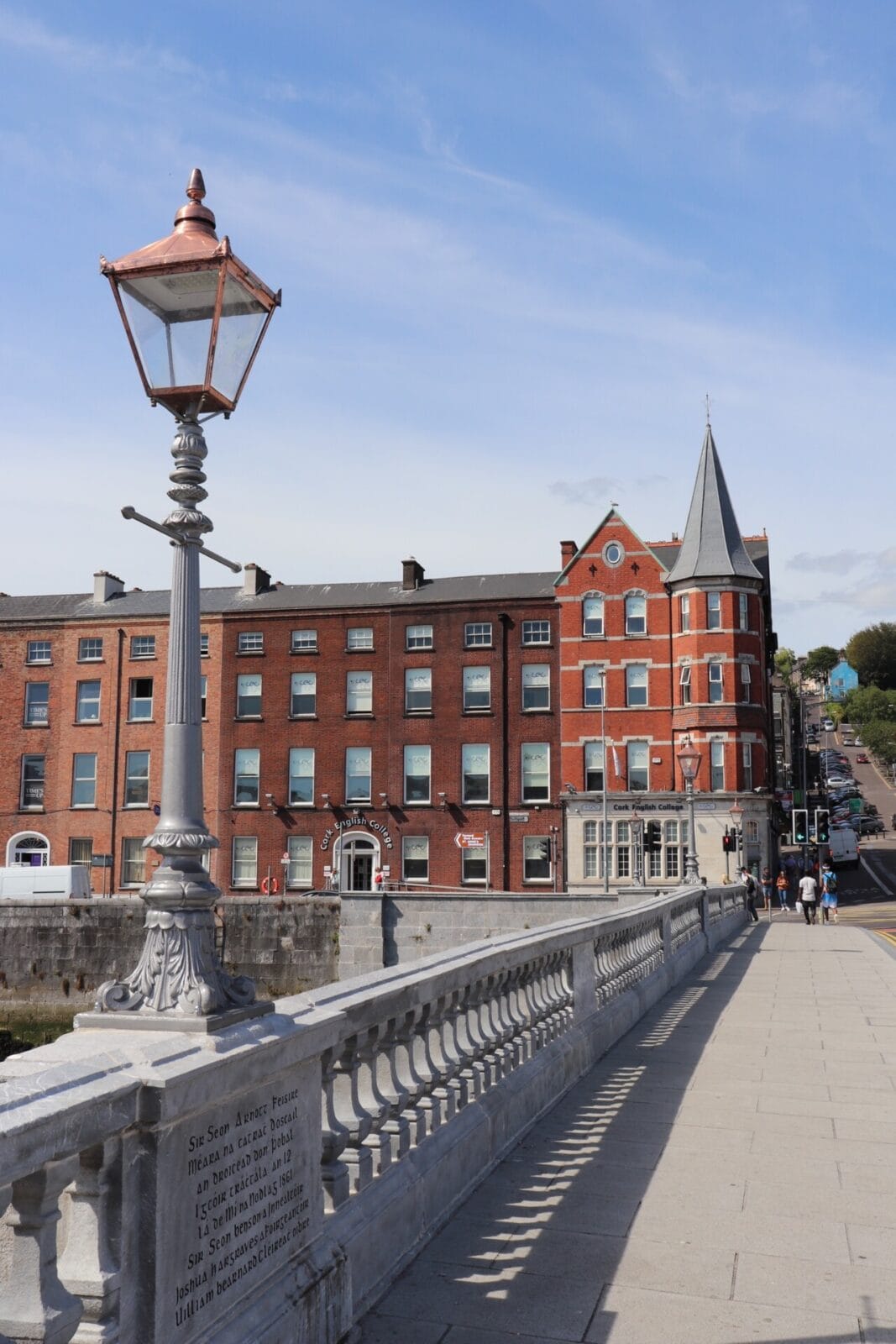 Historische Brücke mit Laterne und roten Backsteingebäuden in Cork, Irland.