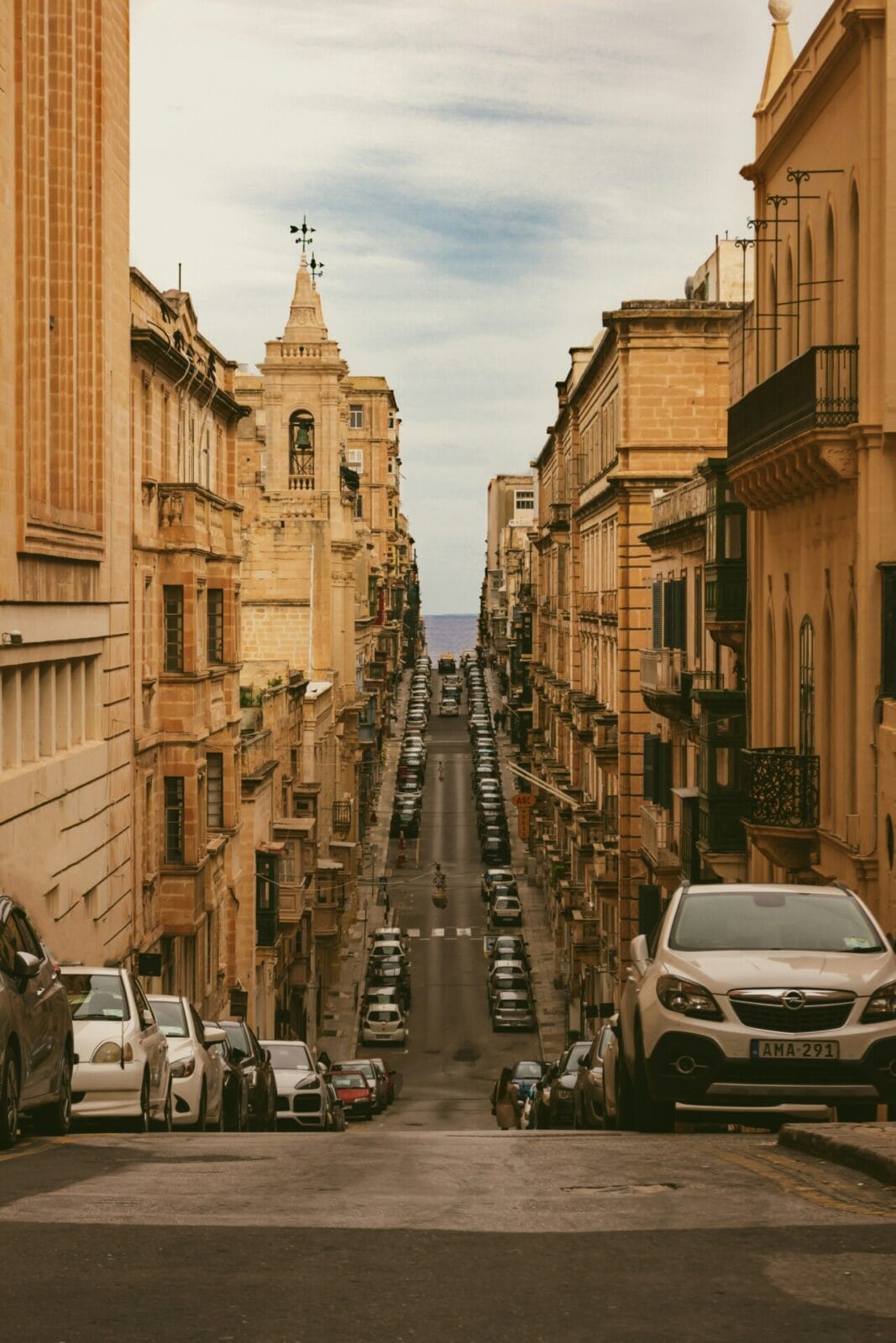 Historische Straße in Valletta, Malta, mit typisch maltesischer Architektur und Blick auf das Mittelmeer.