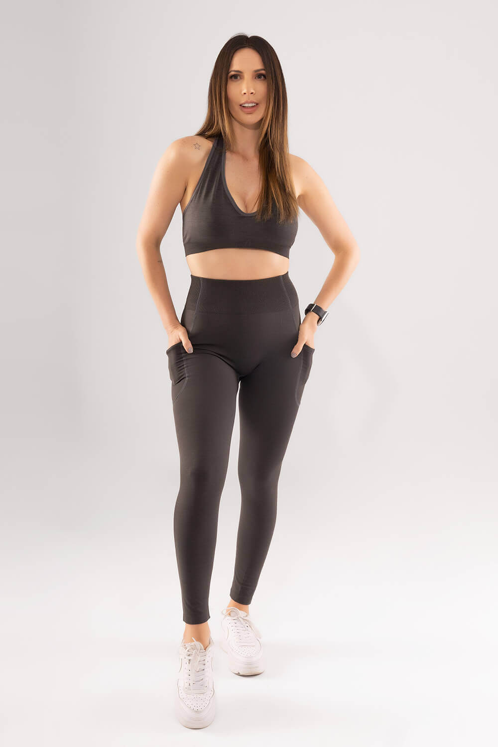 mujer de frente luce top y leggins deportivo con bolsillos color gris oscuro