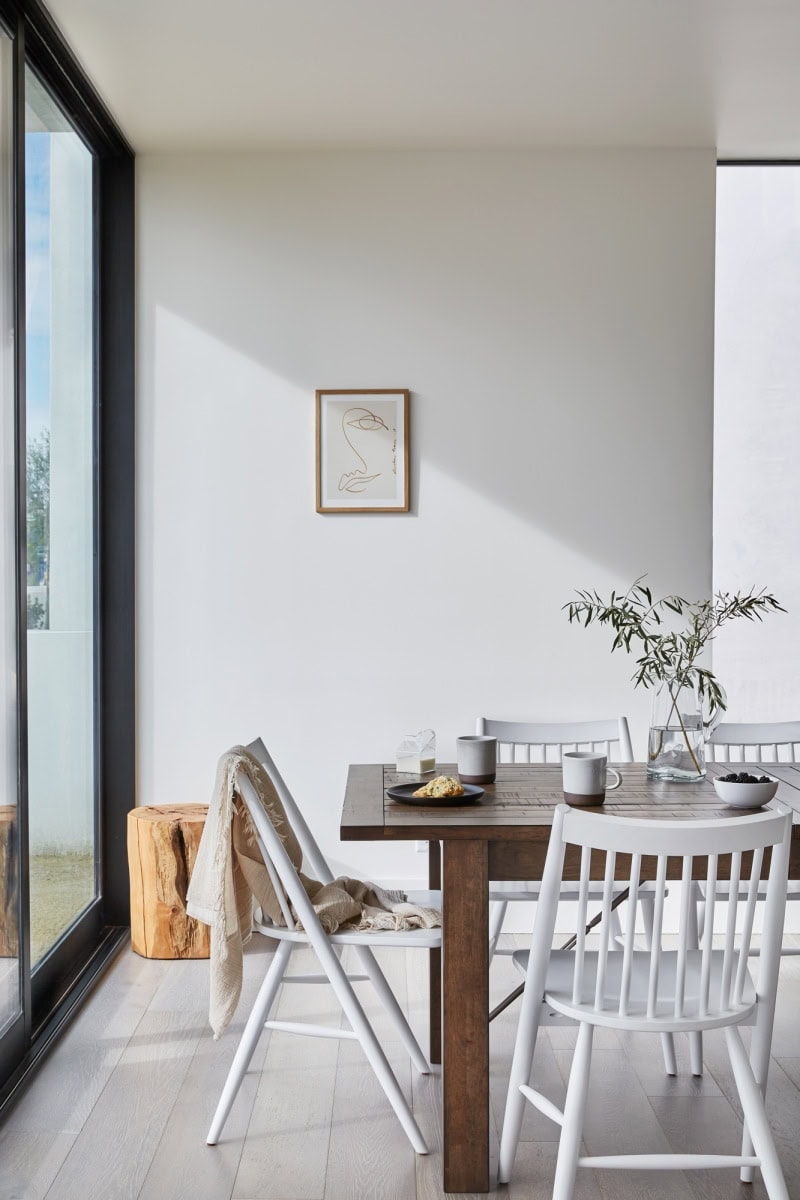 Contemporary dining room with minimalist decor and natural light from large windows.