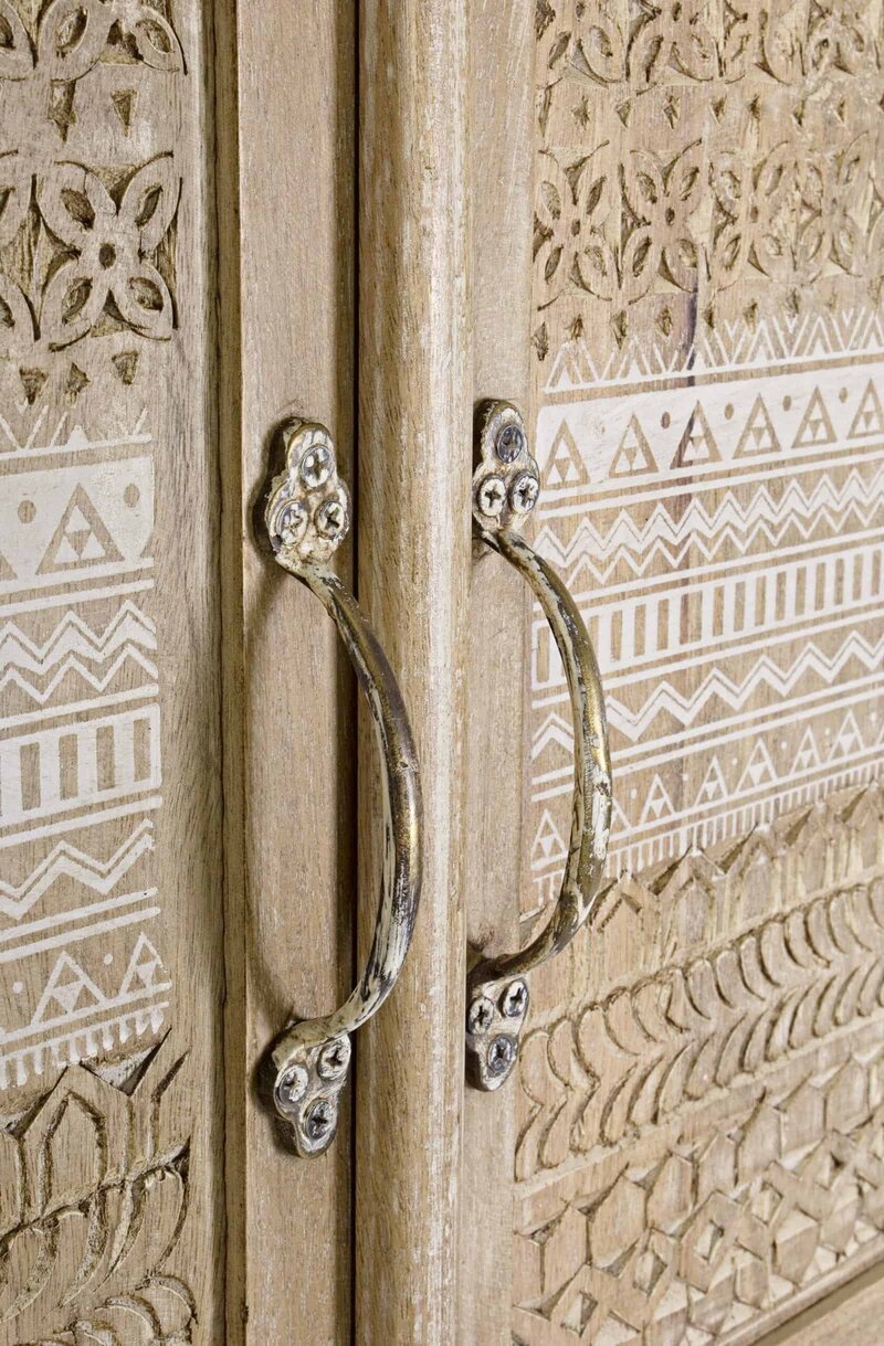 Maniglia rustica su porta in legno intagliato con motivi etnici.