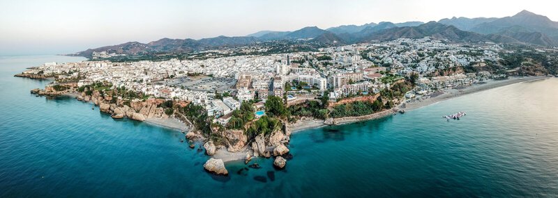 Panoramablick auf Nerja an der Costa del Sol mit Bergen im Hintergrund und dem Mittelmeer im Vordergrund