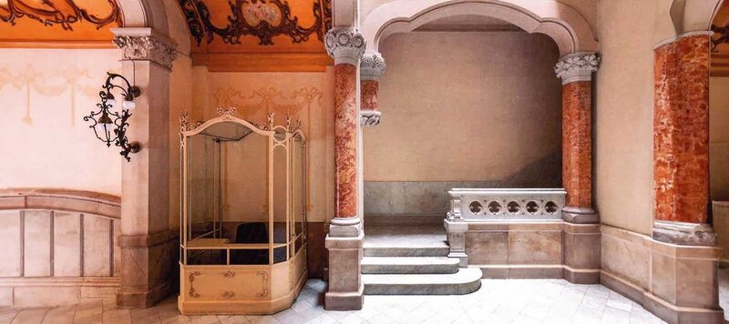 Prächtiger Innenraum im Jugendstil mit kunstvollen Marmorsäulen, geschwungenen Bögen und einer antiken Empfangskabine.
