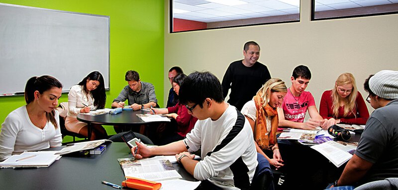 Internationale Studierende arbeiten gemeinsam an Lernmaterialien in einem modernen Klassenzimmer.